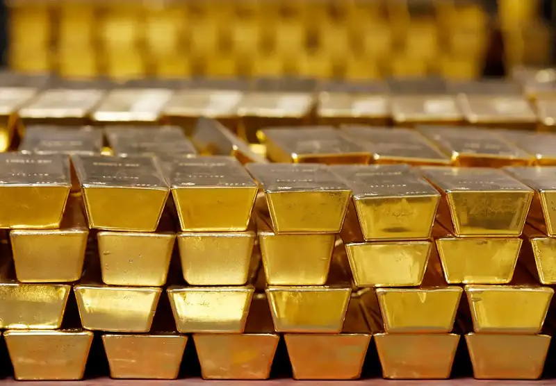 Gold bars and coins with fluctuating market graphs